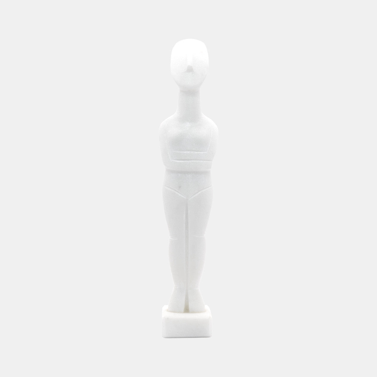 The image shows a stylised white statue or figurine made from White Naxos Marble. It is a simplified representation of a human figure with an abstract and geometric design. The figure has no facial features and stands upright on a small base. The aesthetic is minimalist, focusing on form and shape rather than detail.