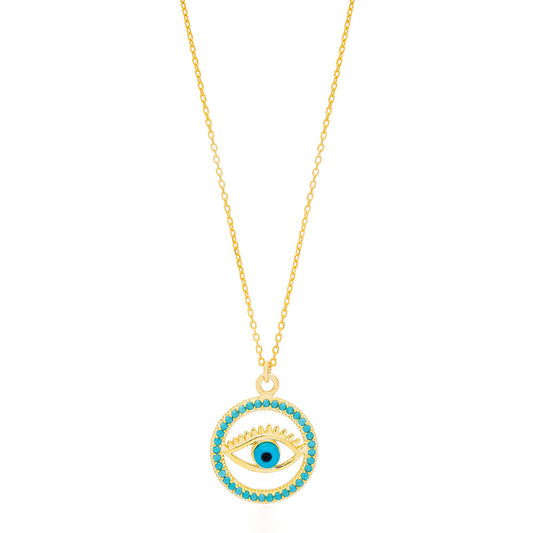 The image shows a gold-colored necklace with a pendant that features the design of an eye. The eye is centered within a circular frame, and the frame is embellished with what appears to be turquoise-colored stones or crystals. The eye itself has a blue iris, which stands out against the gold and turquoise colors. This type of design is often associated with the "evil eye" talisman, which is believed in various cultures to protect the wearer from bad luck or harmful energies.