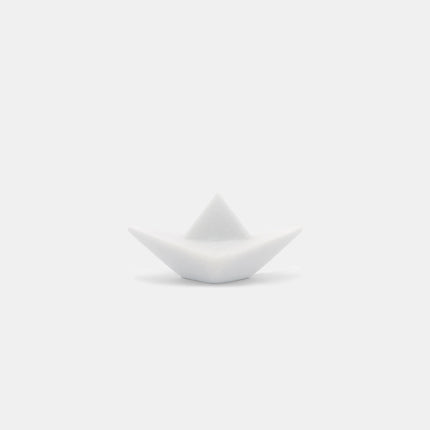 The photograph portrays an elegant sculpture of an origami paper boat, expertly crafted from pristine Naxos Marble. This m...