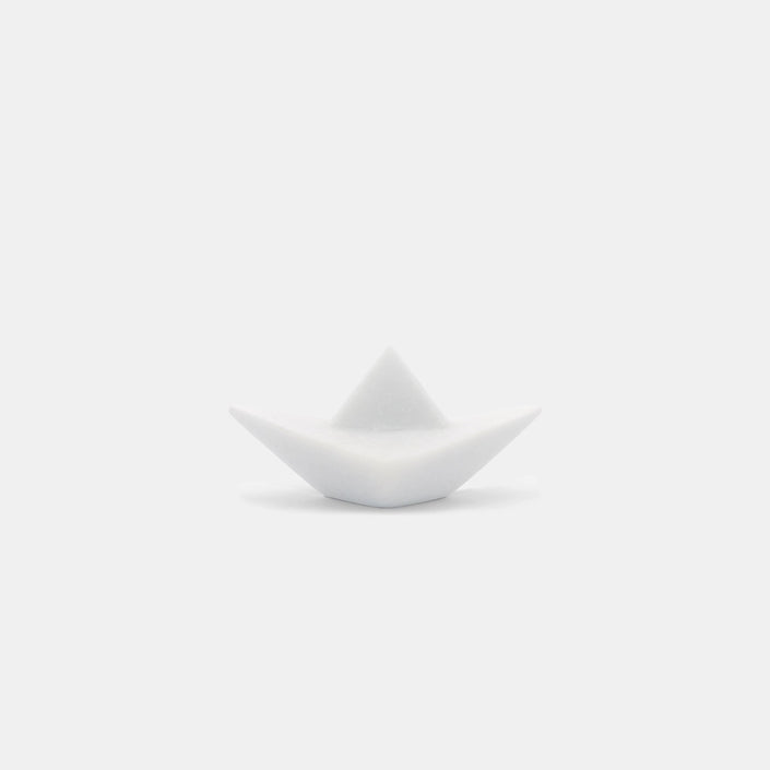 The photograph portrays an elegant sculpture of an origami paper boat, expertly crafted from pristine Naxos Marble. This m...