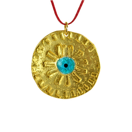 Close up of round evil eye disc, pendant in gold-plated silver