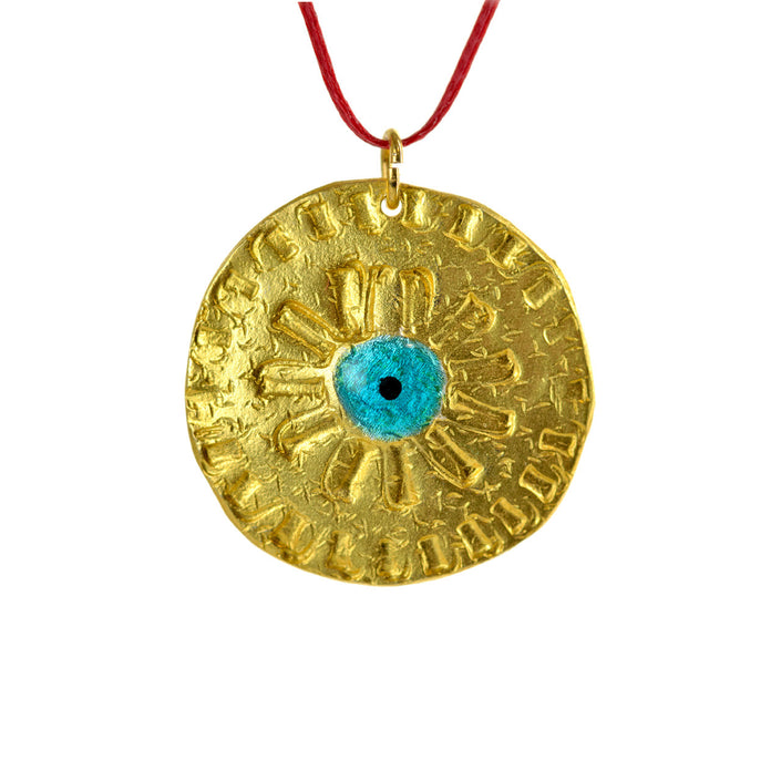 Close up of round evil eye disc, pendant in gold-plated silver