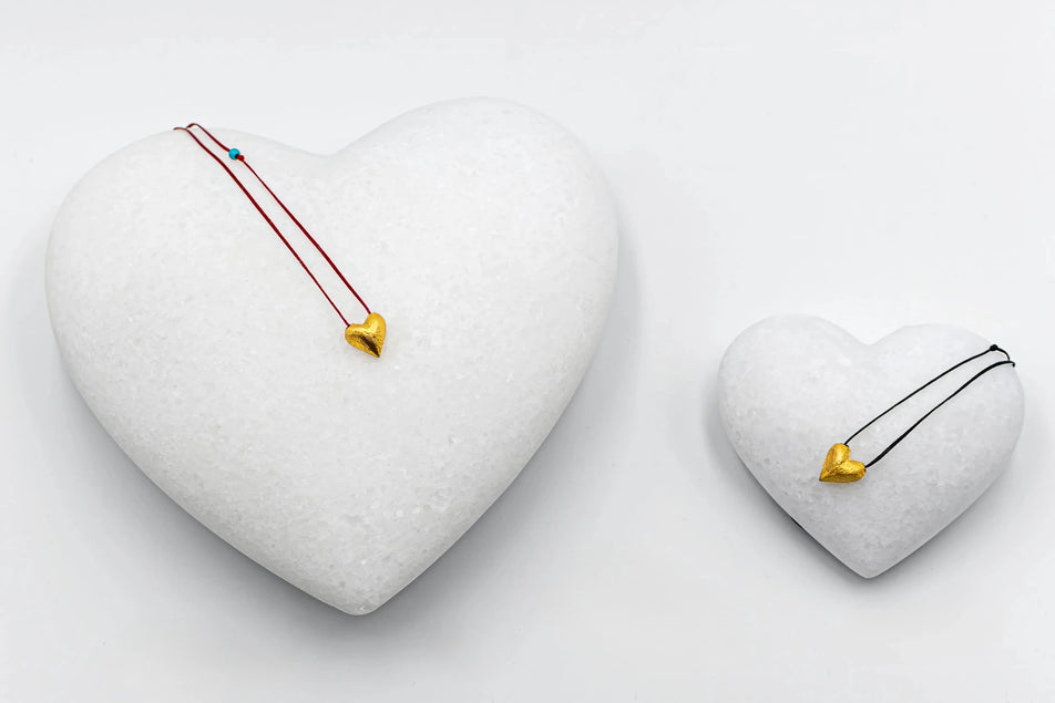 Handmade gold heart pendant necklaces displayed on marble hearts at Tereza’s Greek Concept Store in Naxos Old Town