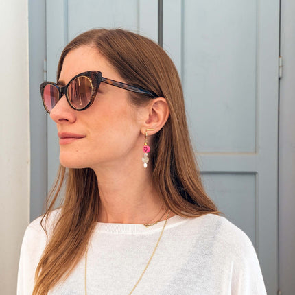 Close up of pearly double smiley hoop earrings in fuschia