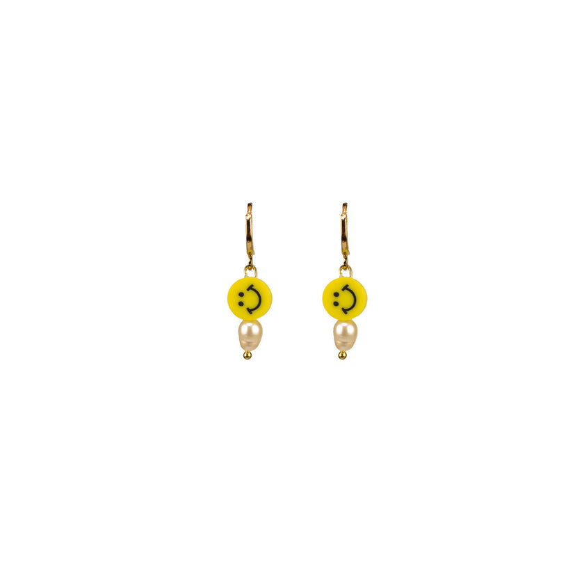 Close up of pearly smiley hoop earrings in bright yellow