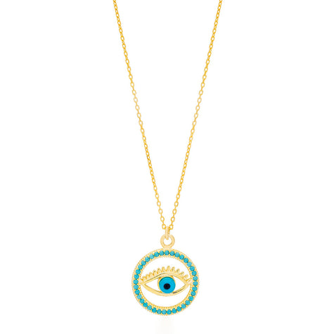 The image shows a gold-colored necklace with a pendant that features the design of an eye. The eye is centered within a circular frame, and the frame is embellished with what appears to be turquoise-colored stones or crystals. The eye itself has a blue iris, which stands out against the gold and turquoise colors. This type of design is often associated with the 
