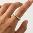 Closeup of an adjustable gold evil eye ring with blue enamel eye details and clear crystals worn on a hand