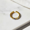 Adjustable gold evil eye ring with alternating blue enamel eye motifs and sparkling clear crystals on a white marble surface