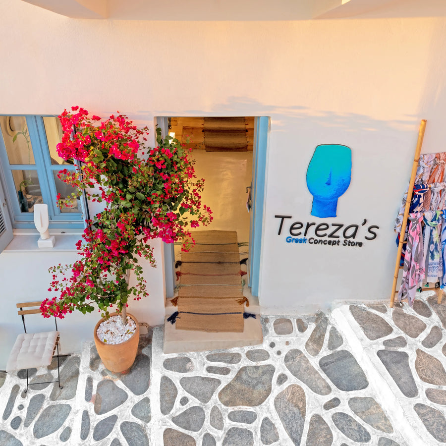 Storefront with 'Tereza's' sign and floral decorations on a stone pavement.
