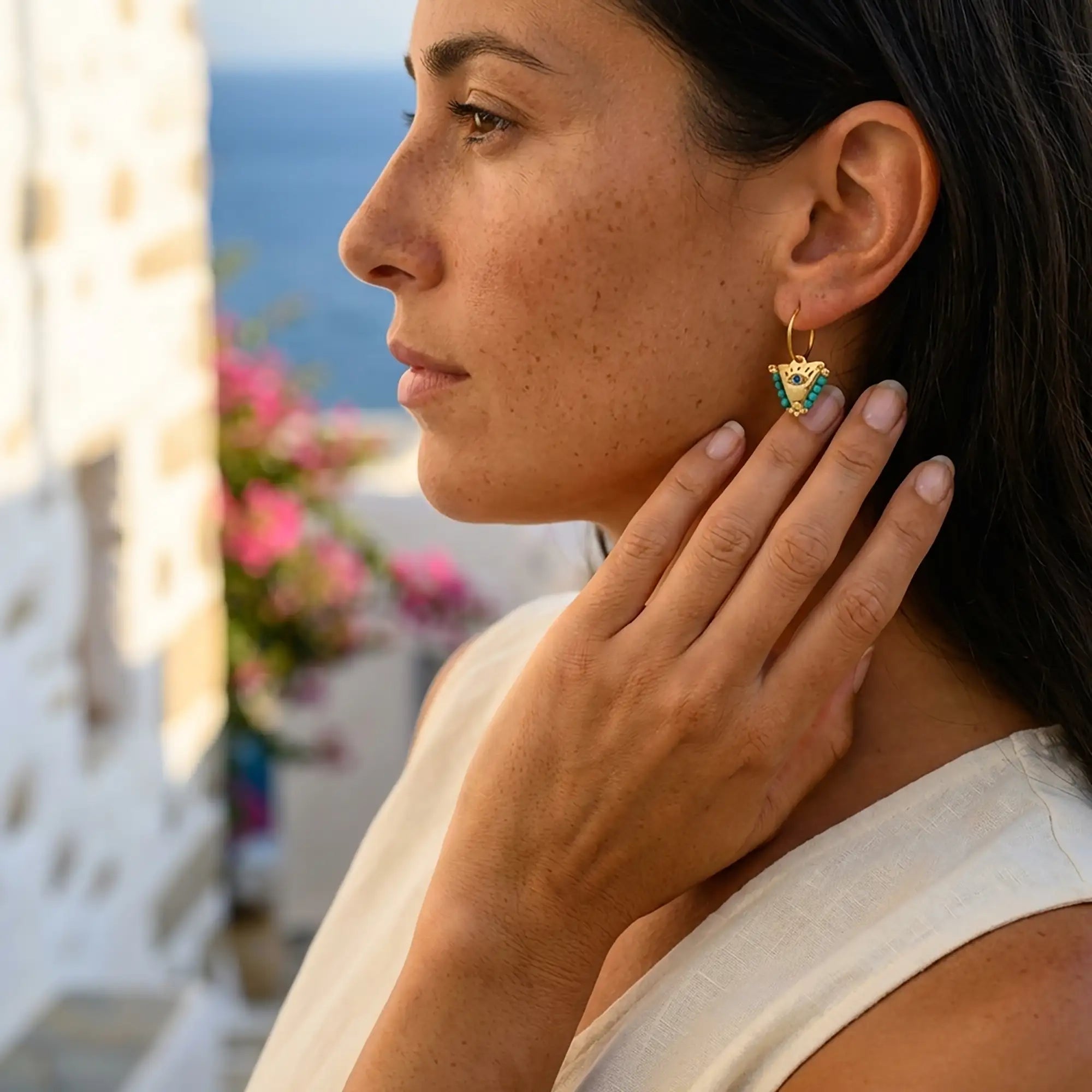 Woman wearing medium Aegean mint fylachto earrings in gold plated sterling silver by the sea