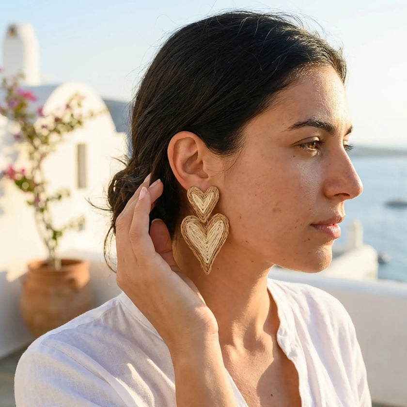 Woman wearing double heart woven statement earrings in a natural straw look