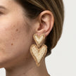 Woman wearing double heart woven statement earrings in a natural straw look