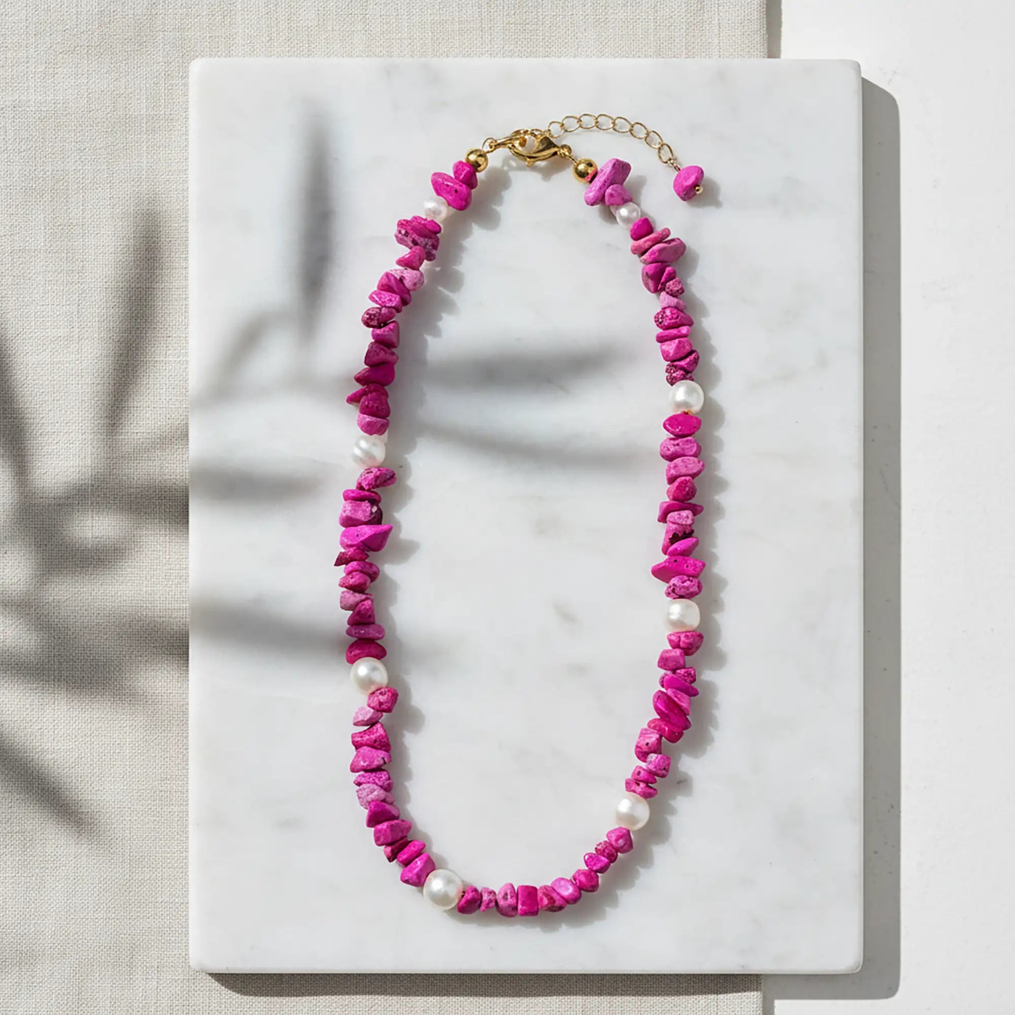 Handcrafted Greek fuchsia necklace with pearls displayed on a flat lay naxos marble surface