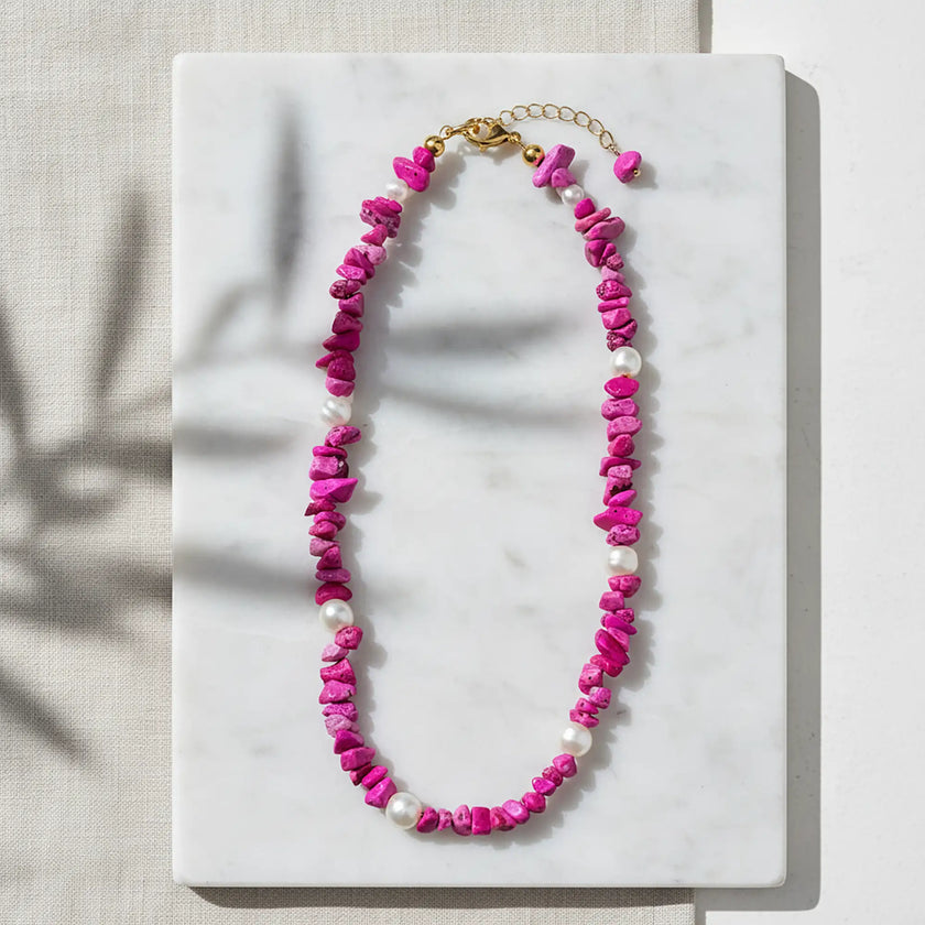 Handcrafted Greek fuchsia necklace with pearls displayed on a flat lay naxos marble surface