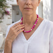 Woman wearing a fuchsia necklace with pearls handcrafted in Greece