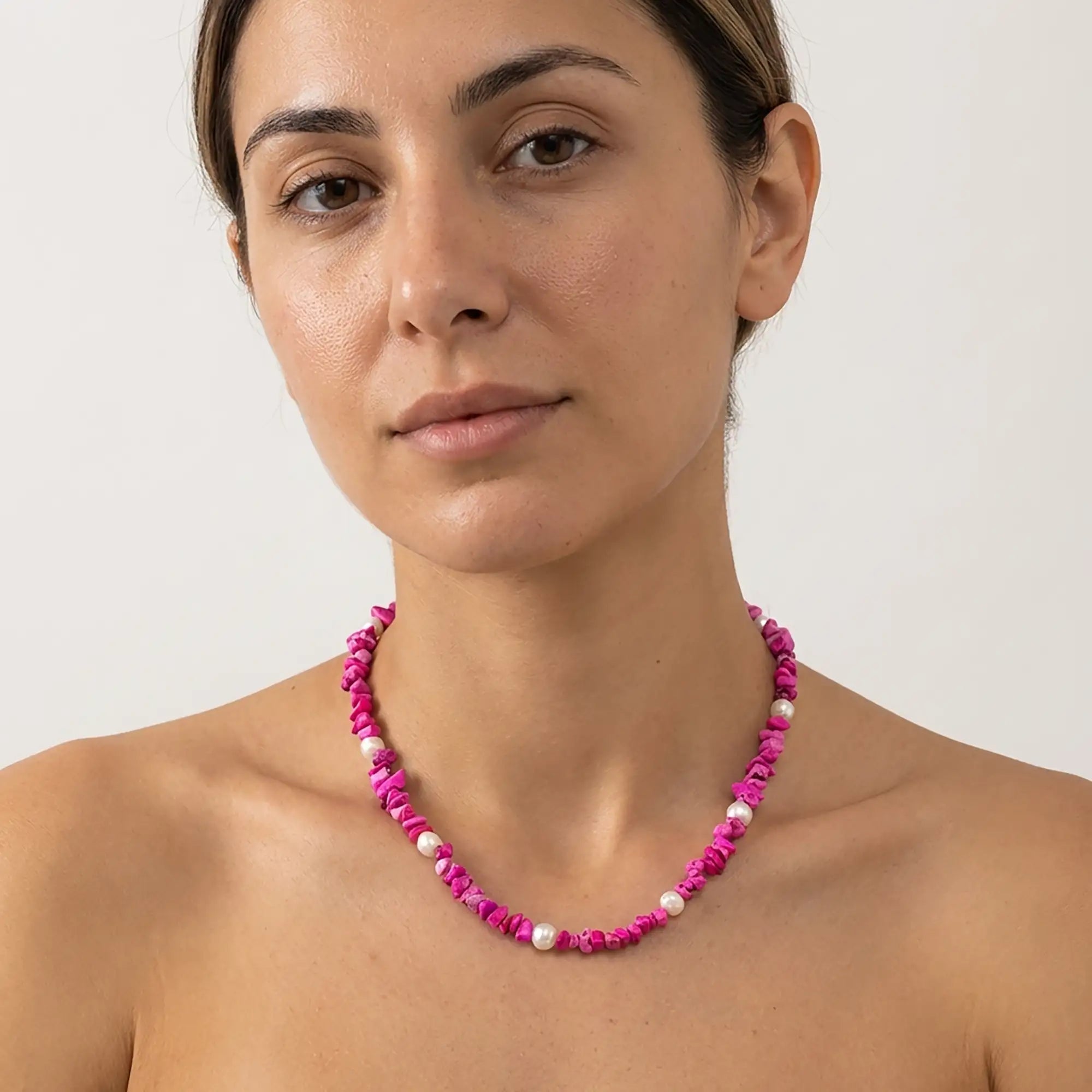 Bold fuchsia beaded necklace with white pearls worn by model in Mediterranean setting