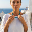 Woman wearing Oh, Coral turquoise necklace with pearl accents in a Greek island setting