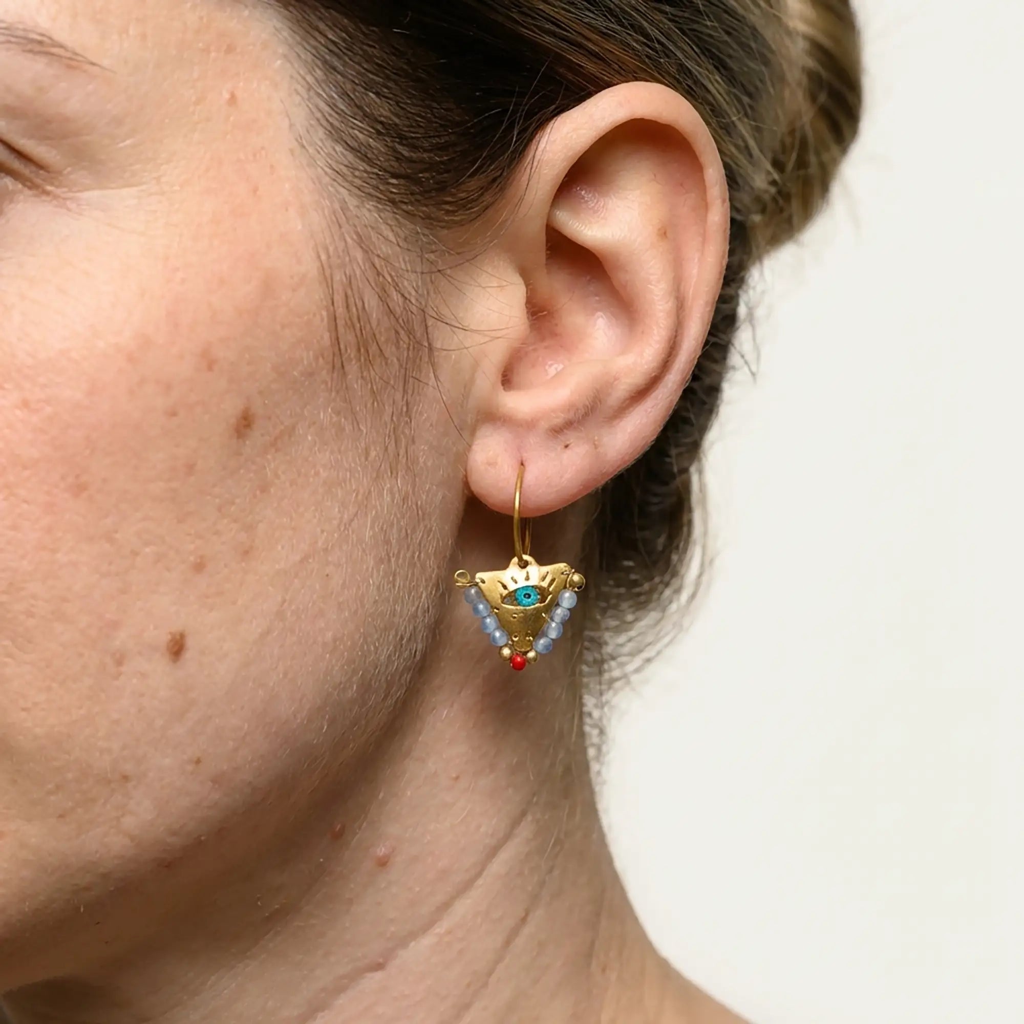 Close up of small elephant gray and coral fylachto earring in gold plated sterling silver with handpainted eye