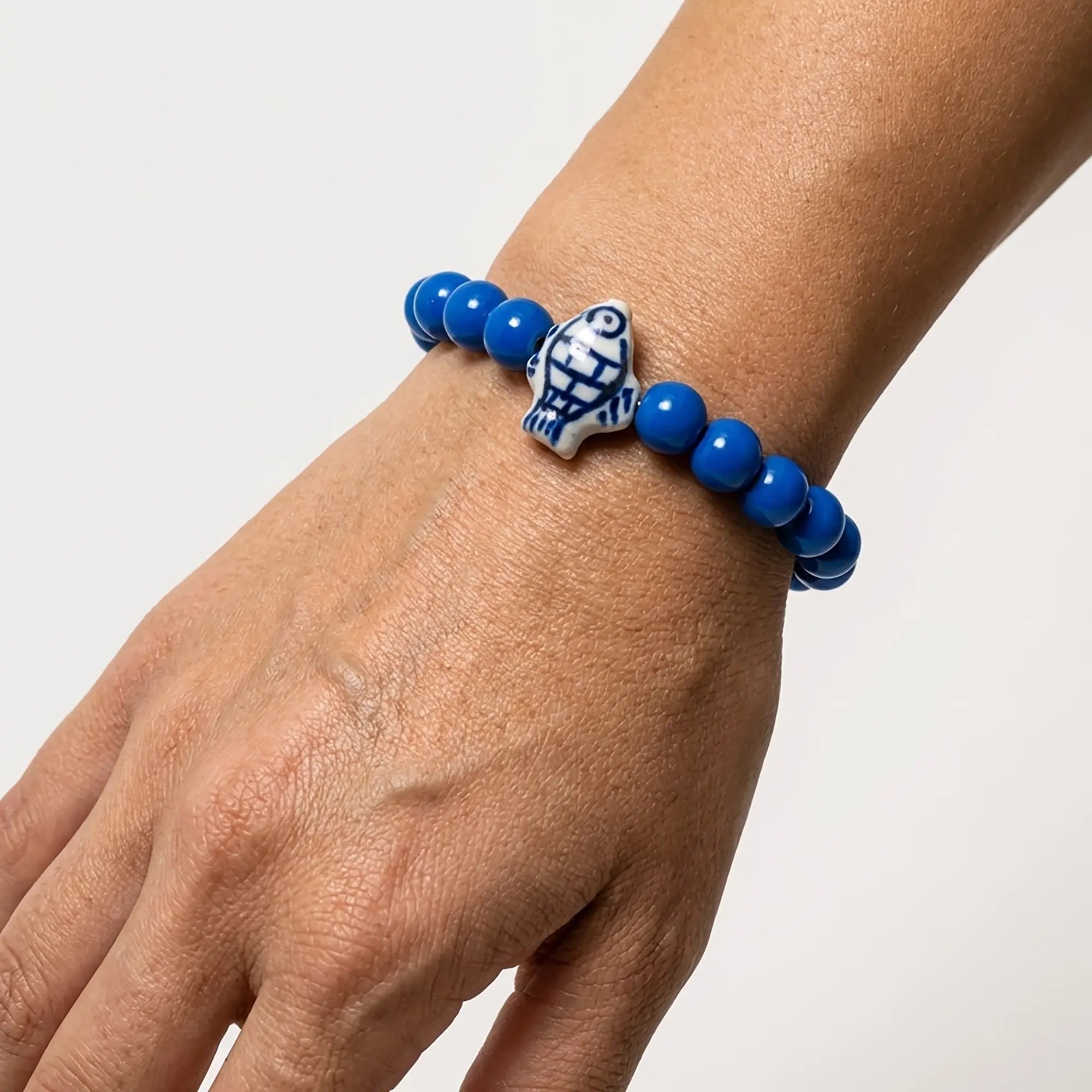Woman wearing a handmade blue bracelet with decorative fish bead
