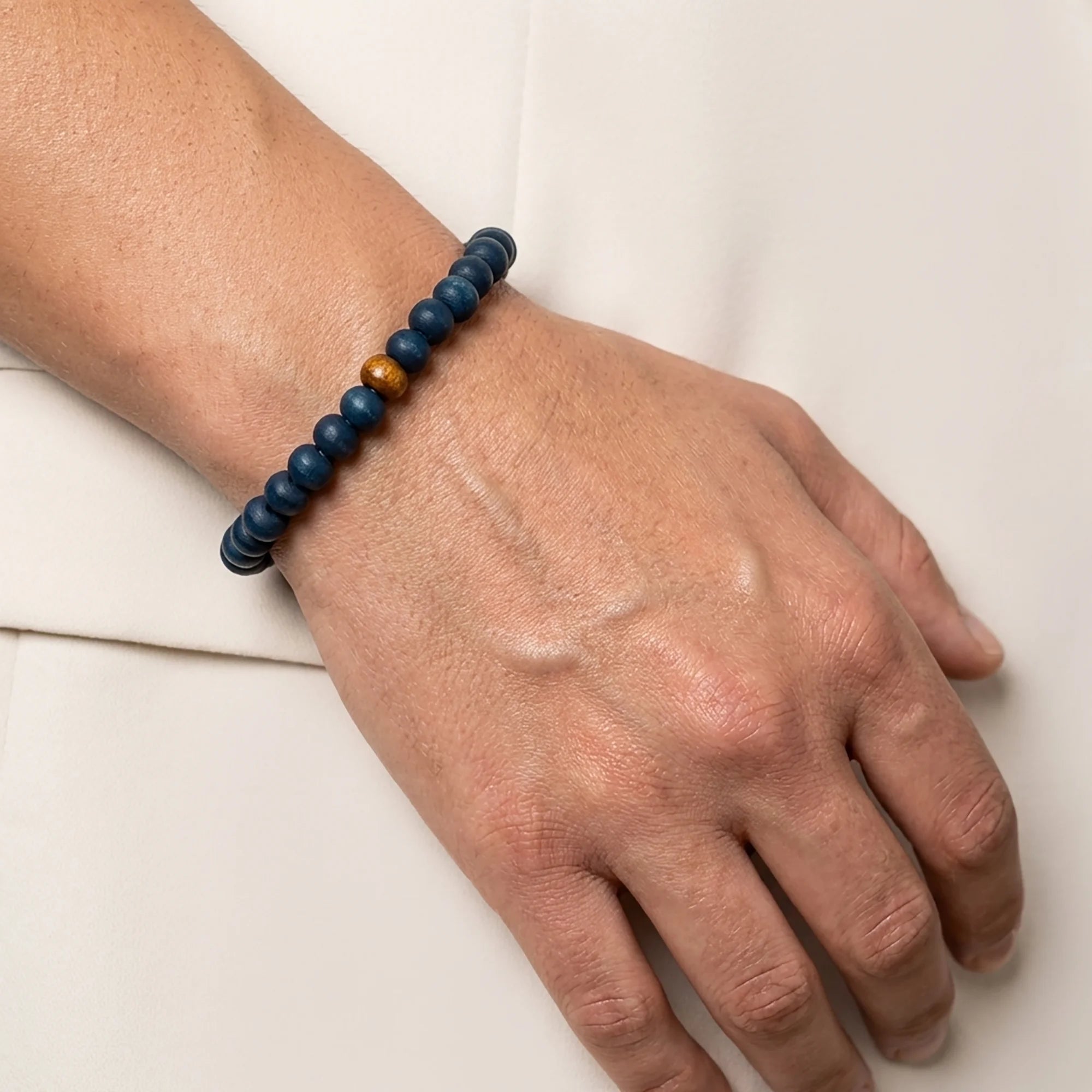 Woman wearing a handmade deep blue wooden bead bracelet with natural wood accents