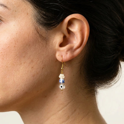 Close up of handmade Greek earrings with rose bead and tiny evil eye detail