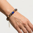 Woman wearing a handmade bracelet with marbled brown beads and blue Murano focal bead