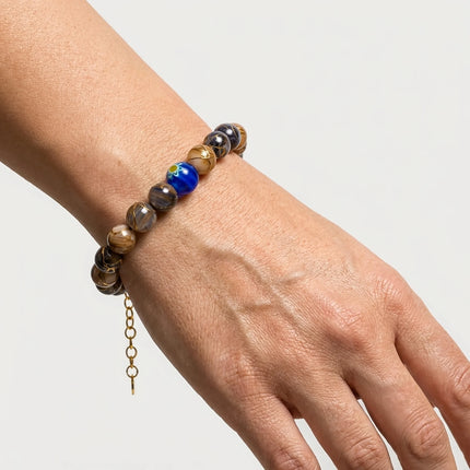Woman wearing a handmade bracelet with marbled brown beads and blue Murano focal bead