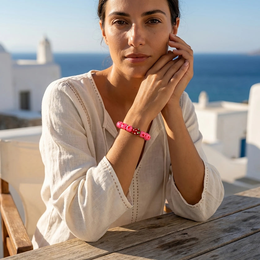 Greek island lifestyle image of a handmade pink bracelet with heart beads and Murano strawberry worn in Naxos