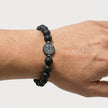 Woman wearing a handmade black lava stone bracelet with tree of life center detail