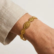 Woman wearing a gold tone stainless steel cuff bracelet with oval sun motif medallions