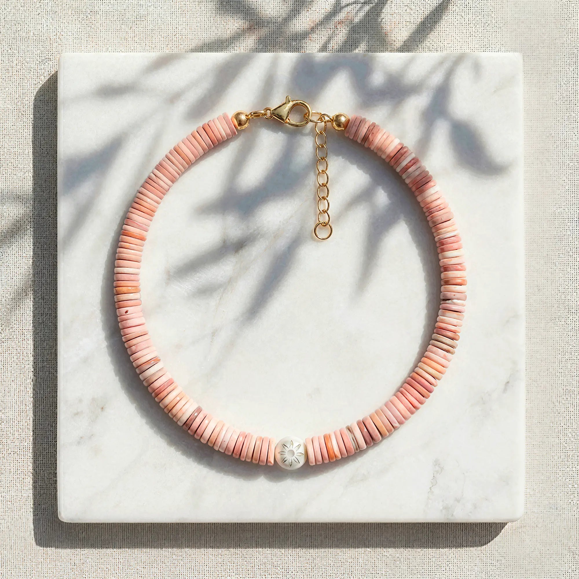 Koralli coral shell disc necklace with Murano glass flower bead styled on marble