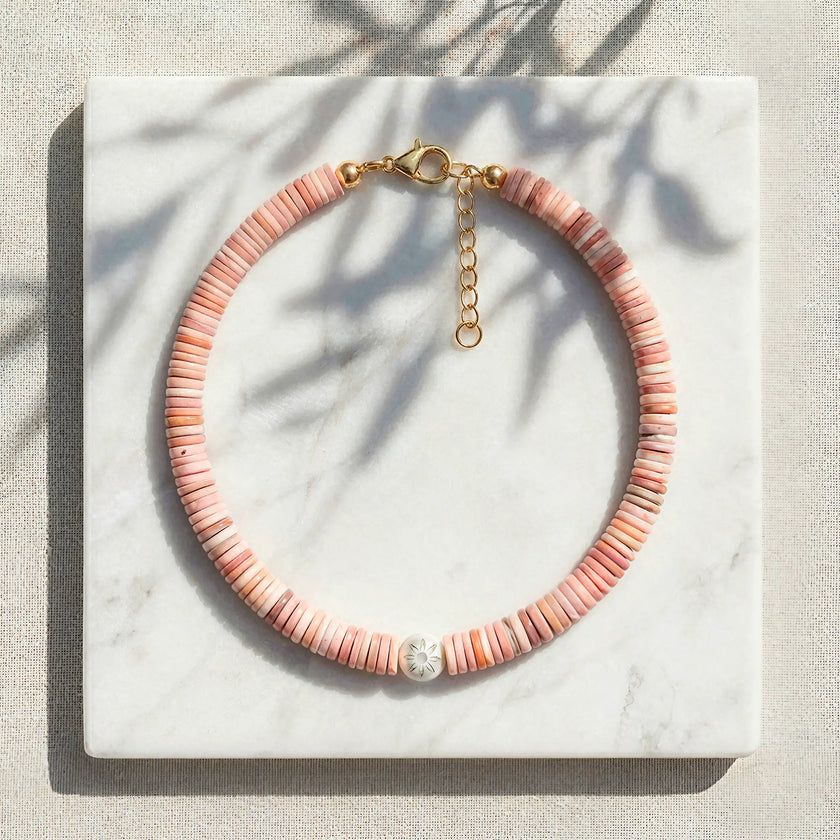 Koralli coral shell disc necklace with Murano glass flower bead styled on marble
