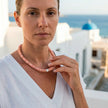 Koralli coral shell necklace worn with white linen against Cycladic backdrop