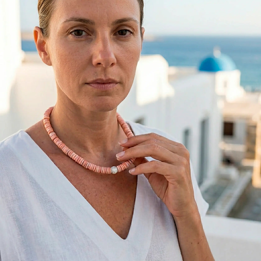 Koralli coral shell necklace worn with white linen against Cycladic backdrop