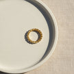 Decorative ring with intricate design on a textured beige surface