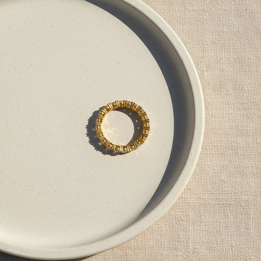 Decorative ring with intricate design on a textured beige surface