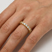 Gold ring with diamonds on a person's finger against a neutral background