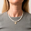 Selini pearl necklace with gold clover pendant worn with grey top