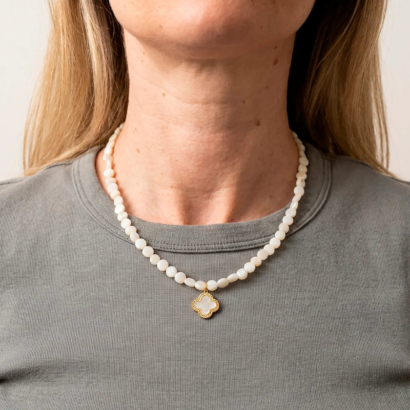 Selini pearl necklace with gold clover pendant worn with grey top