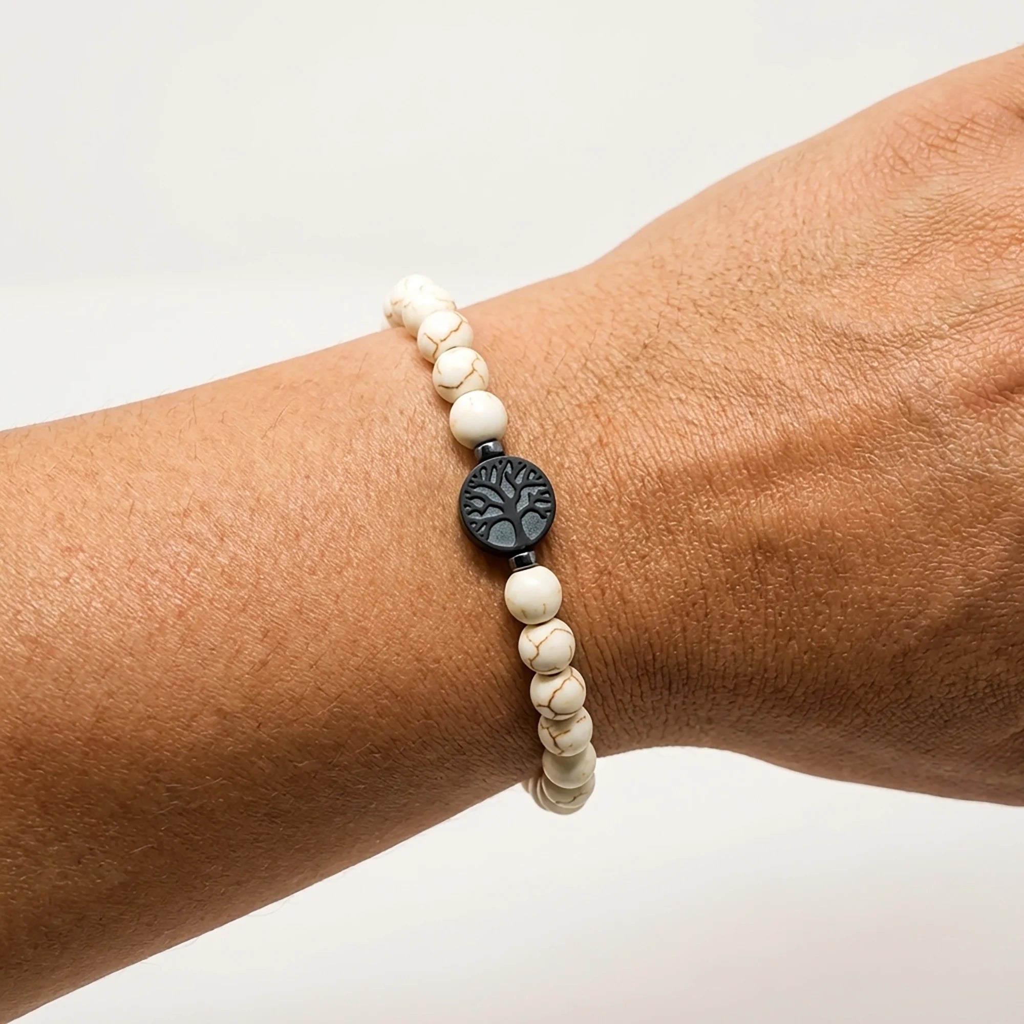 Woman wearing a handmade white stone bracelet with tree of life centerpiece