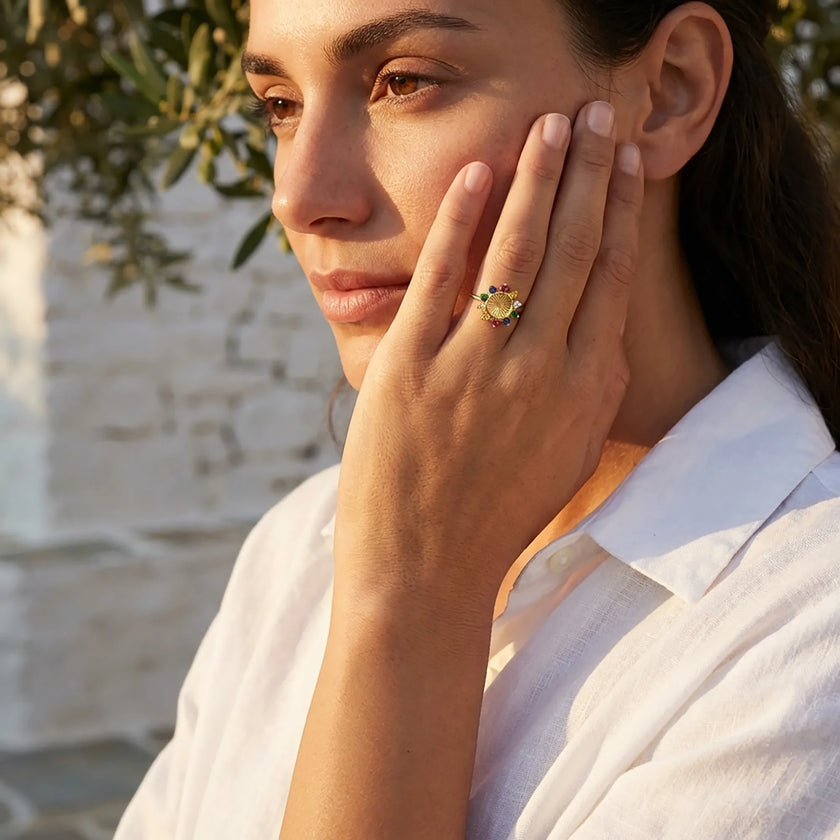 The gold Tereza's zircon flower ring displayed on a white-washed stone surface in natural Greek sunlight.