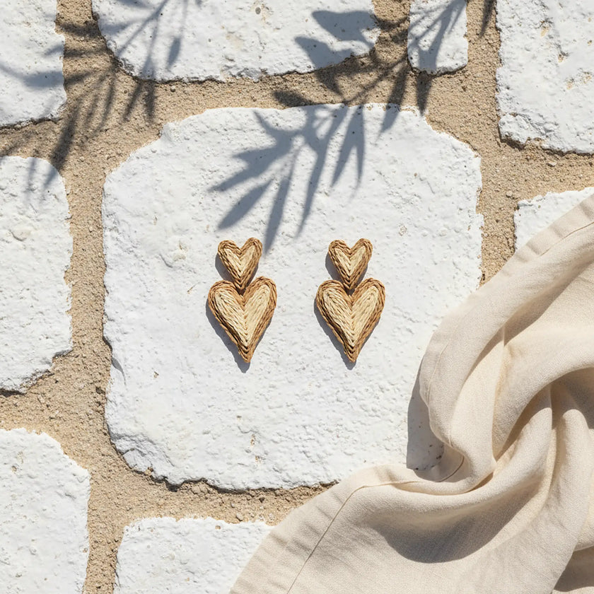Double heart woven earrings with natural texture on white stone background